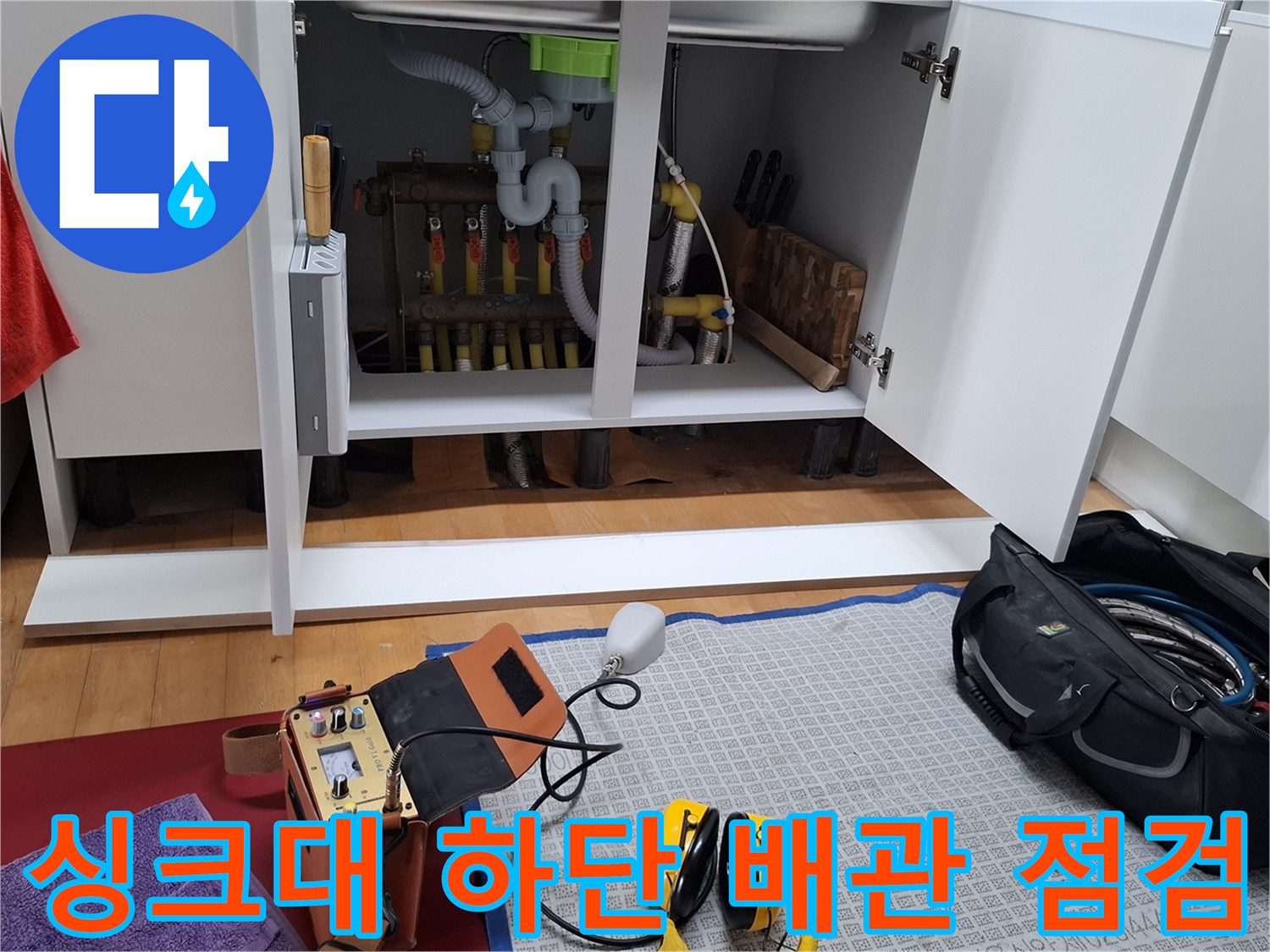 주방 싱크대 아래 분배기 라인과 검사용 정밀 측정 장비의 모습