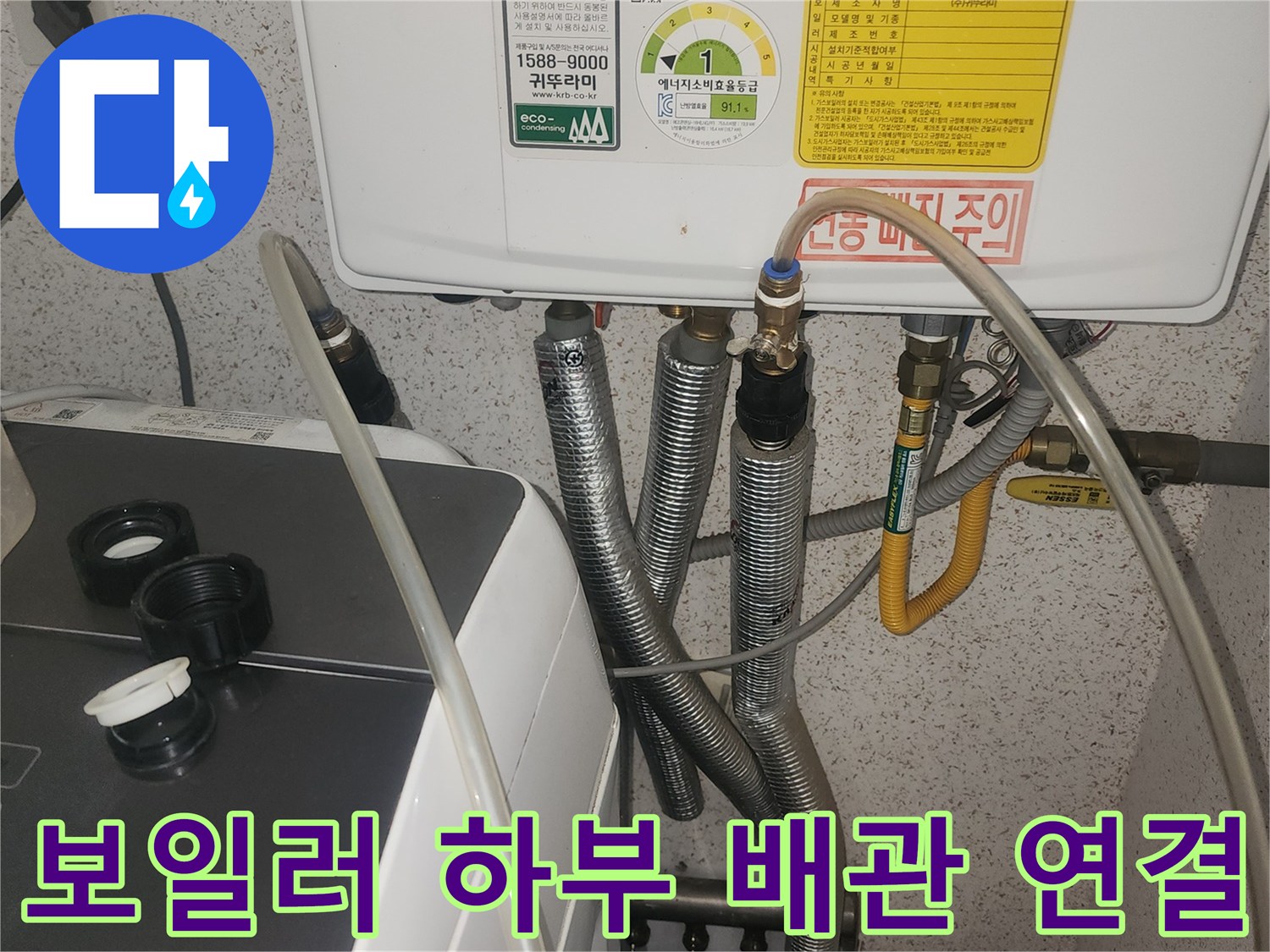보일러 본체 아래에 연결된 금속제 주름관과 노란색 배관입니다.