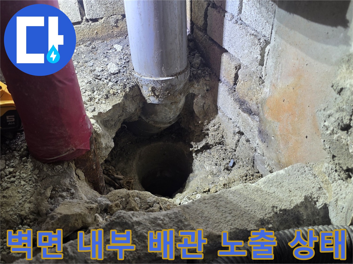 굴착된 벽면 사이로 드러난 하얀색 PVC 배관과 주변 자재들입니다.