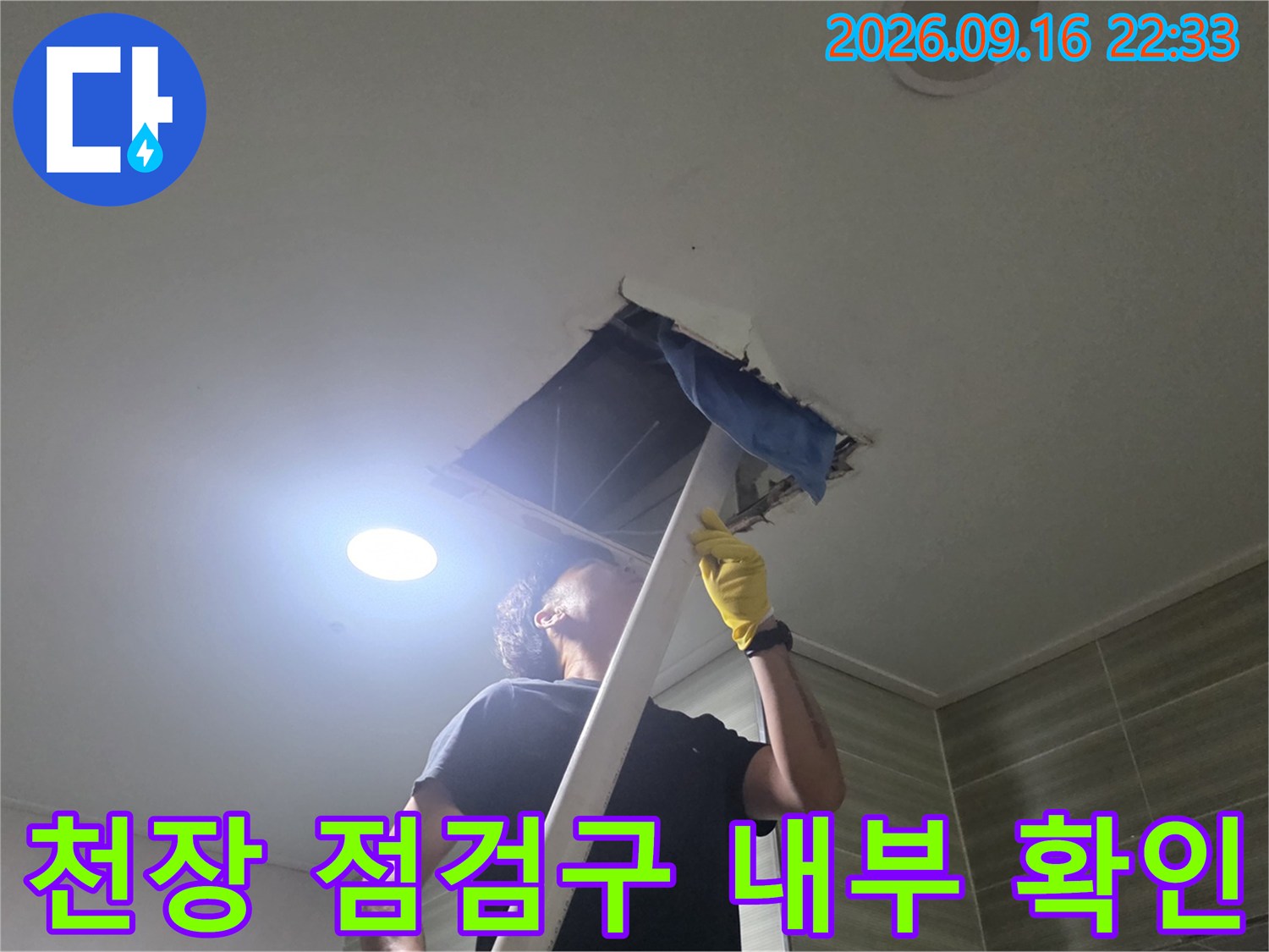 천장 점검구를 열어 배관 상태를 면밀히 확인하는 작업 현장입니다.