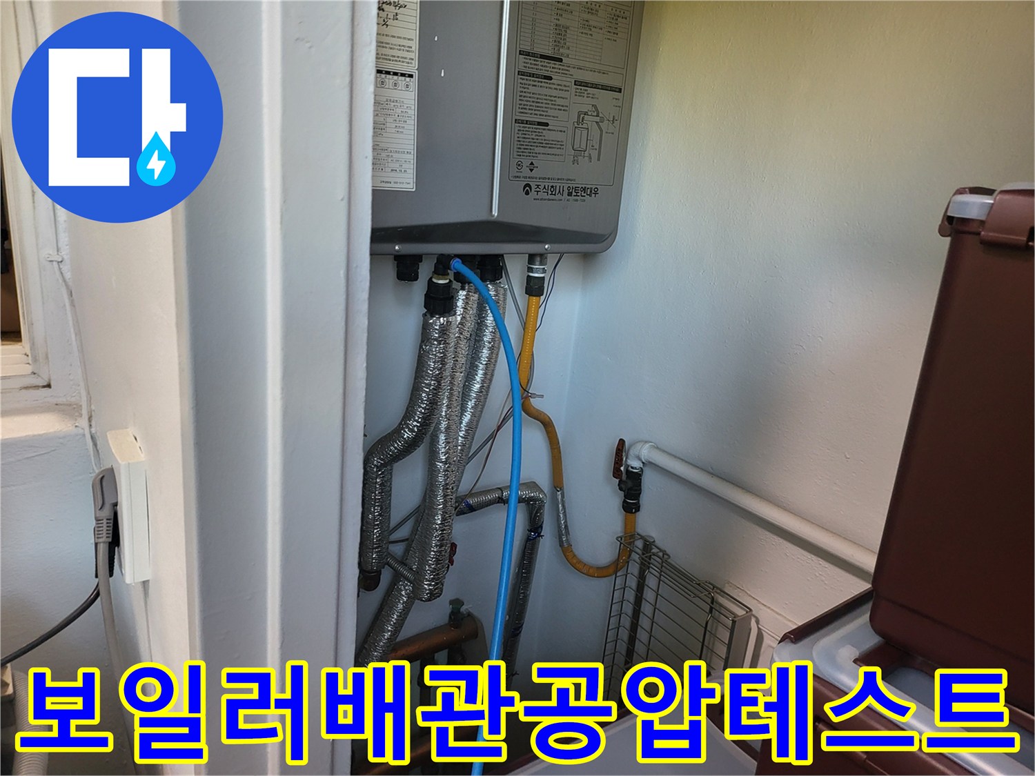 보일러 하부 배관에 연결된 압력 측정 장비와 파란색 호스 모습